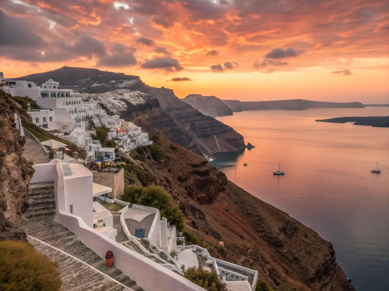 A vibrant image of Santorini, Greece, showcasing the iconic white-washed buildings and blue domes overlooking the Aegean Sea at sunset. The scene captures the romantic and picturesque essence of the island.